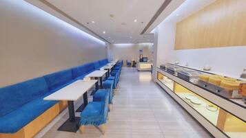 A restaurant with long tables and blue cushioned seating along the walls.