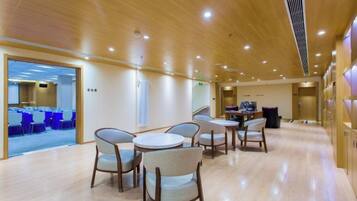 Een moderne hotellobby met houten vloeren, ronde tafels en stoelen.