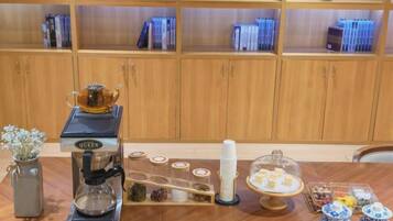 Een koffiehoek met een koffieapparaat, suikerpotten en een theeset.