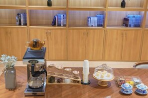 Una estación de café con una cafetera, azúcar en frascos y un juego de té.