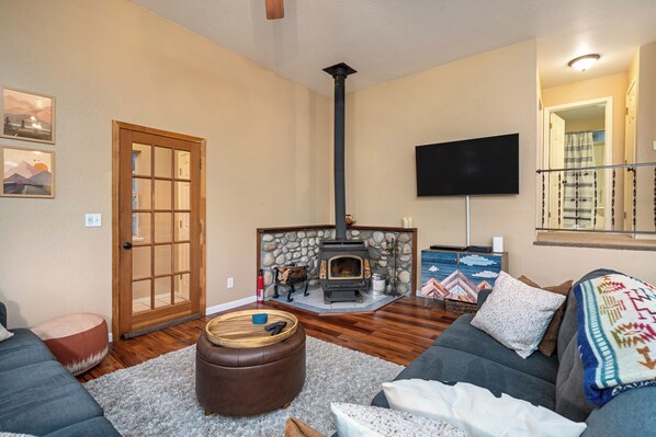 Una sala de estar con chimenea de piedra, un sofá, una mesa de centro y un televisor montado en la pared.