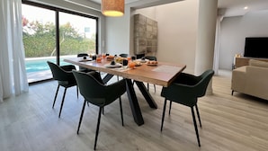 Ein moderner Essbereich mit einem Holztisch, schwarzen Stühlen und einer Pendelleuchte.