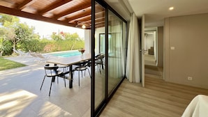 Ein modernes Interieur mit Glaswand zum Poolbereich, Holzboden und Essbereich.