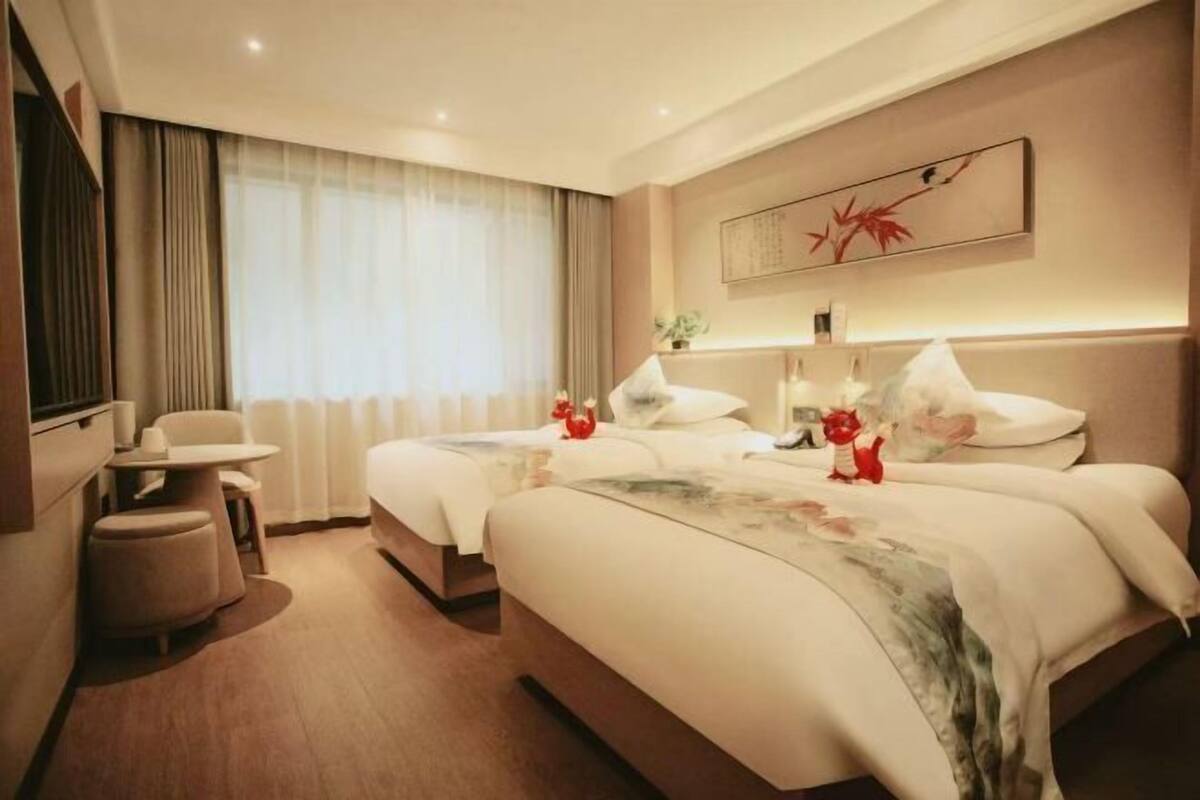A hotel room with two beds, a desk, and a chair.