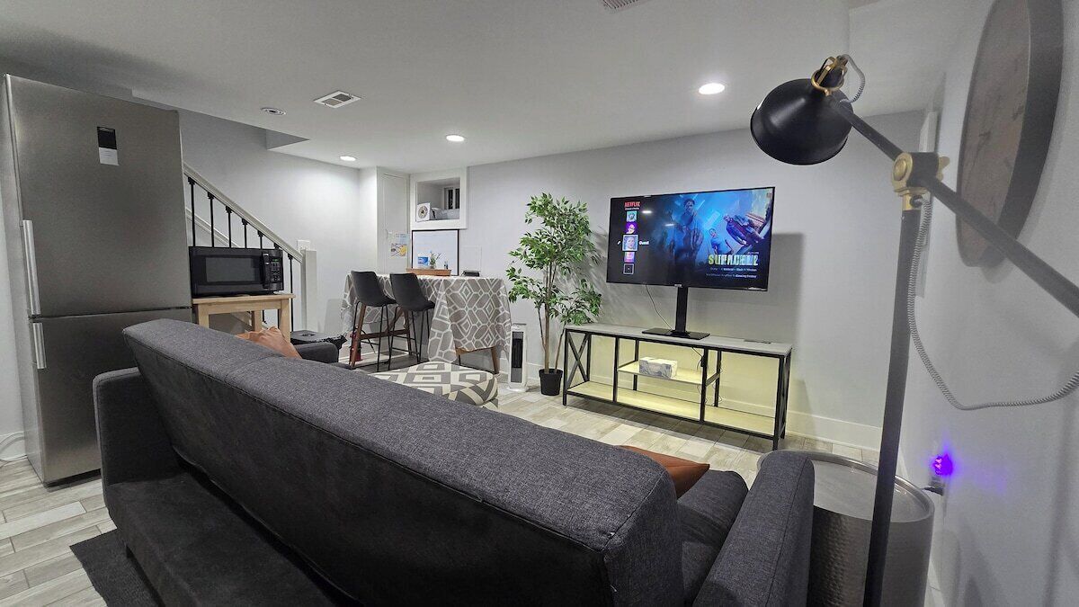 A modern living room with a sofa, a TV, a desk, and a plant.