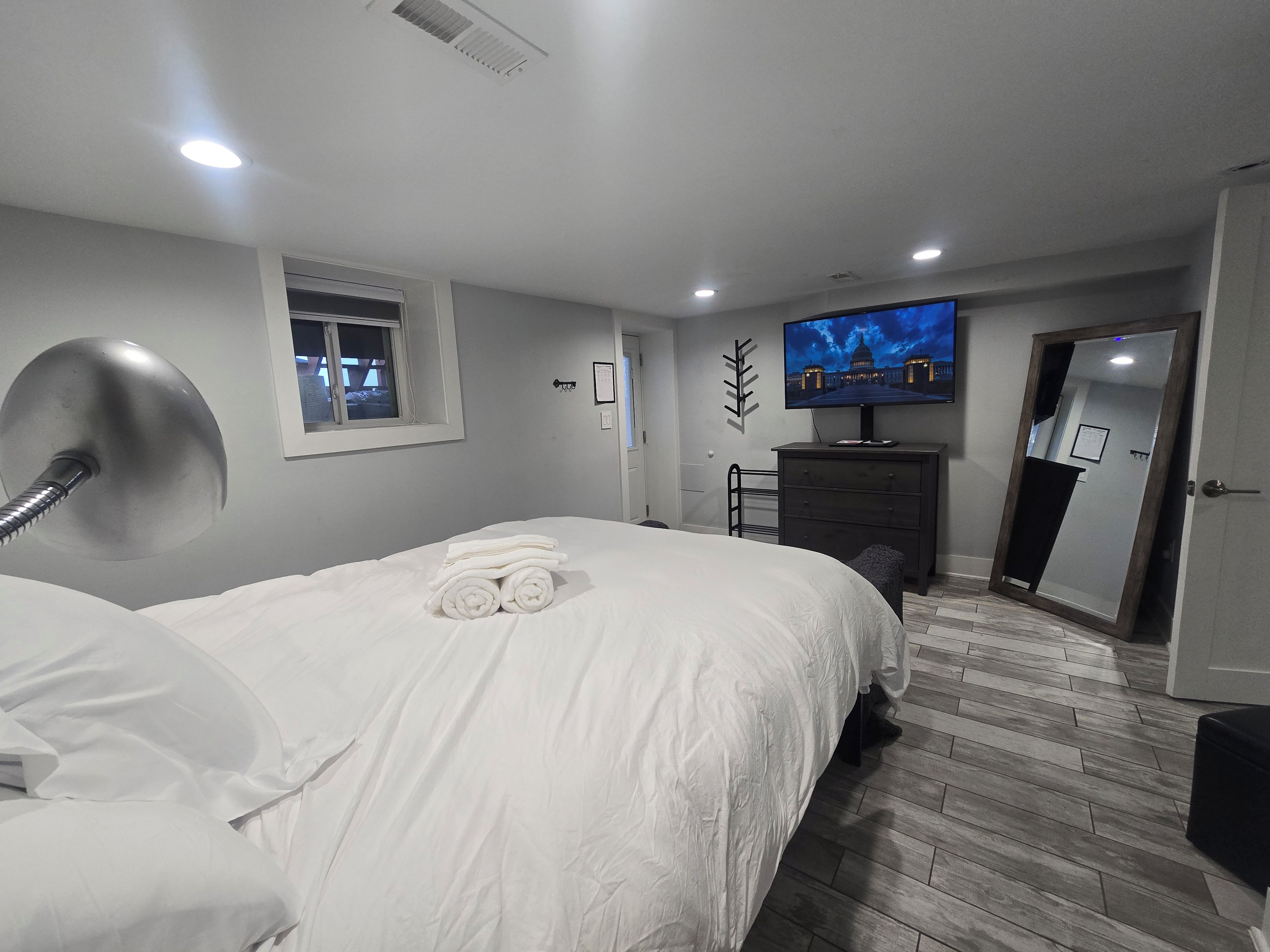 Ein Hotelzimmer mit Bett, Schreibtisch, Fernseher und Spiegel.