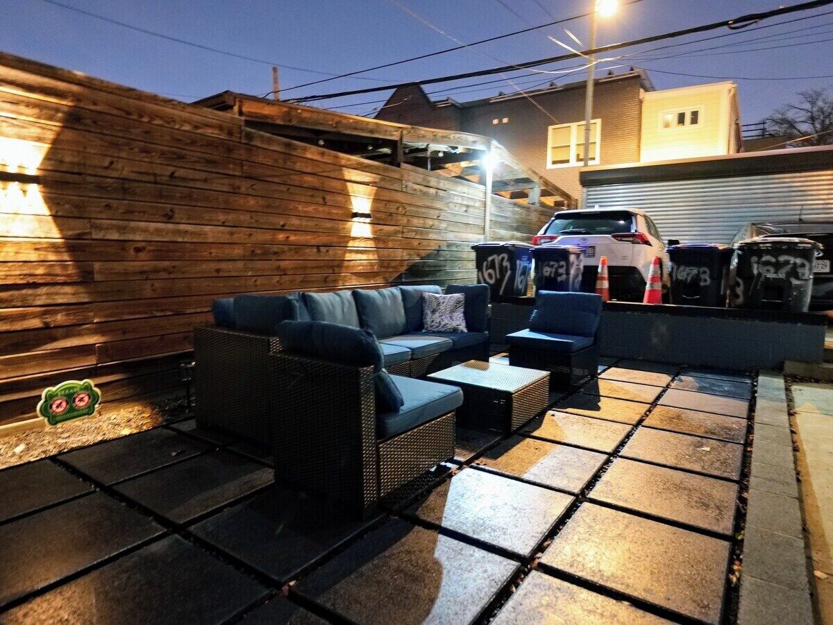 Une terrasse extérieure avec un ensemble de meubles de salon et une voiture garée à proximité.