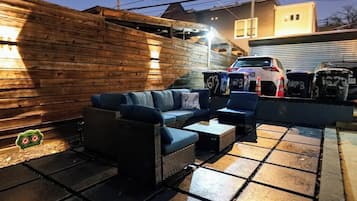 Une terrasse extérieure avec un ensemble de meubles de salon et une voiture garée à proximité.