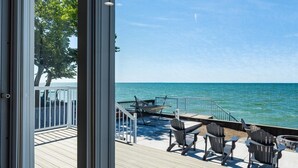 A wooden deck with outdoor seating and a view of the ocean.