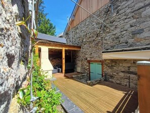 A stone building with a wooden deck and a covered outdoor seating area.