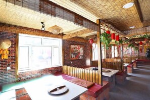 A restaurant interior with brick walls, wooden ceiling, and a large window. - Wuchang Snow Valley Jiaxin Inn (Wuchang)