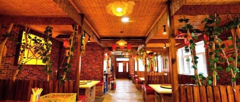 A restaurant with brick walls, wooden benches, and hanging plants.