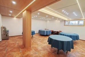 Un salón de conferencias con mesas redondas, un pilar de madera y suelo de baldosas.