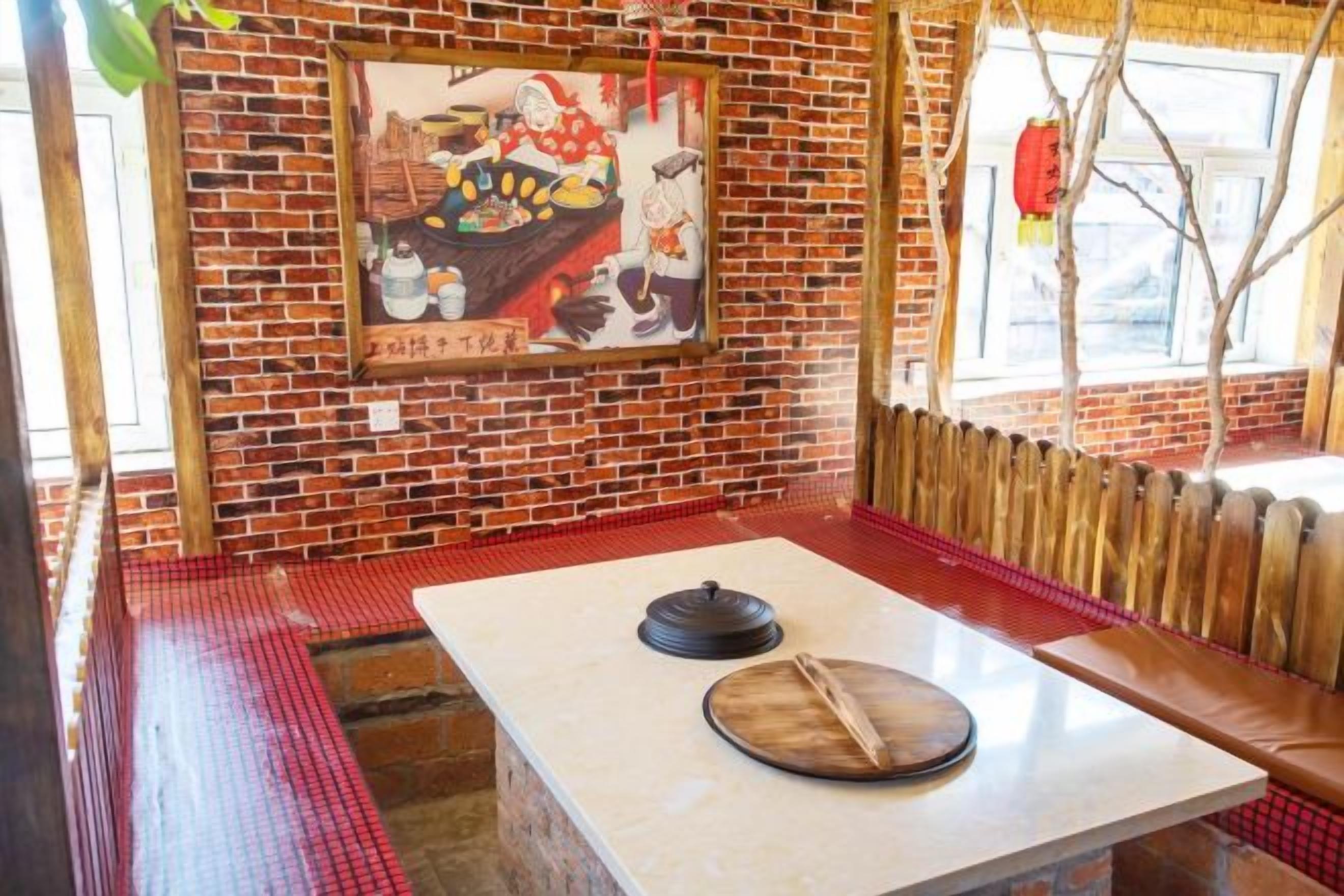 Interior de restaurante con pared de ladrillo, banco de madera, mesa con tapa e imagen enmarcada en la pared.