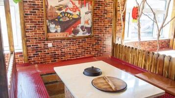 Interior de restaurante con pared de ladrillo, banco de madera, mesa con tapa e imagen enmarcada en la pared.
