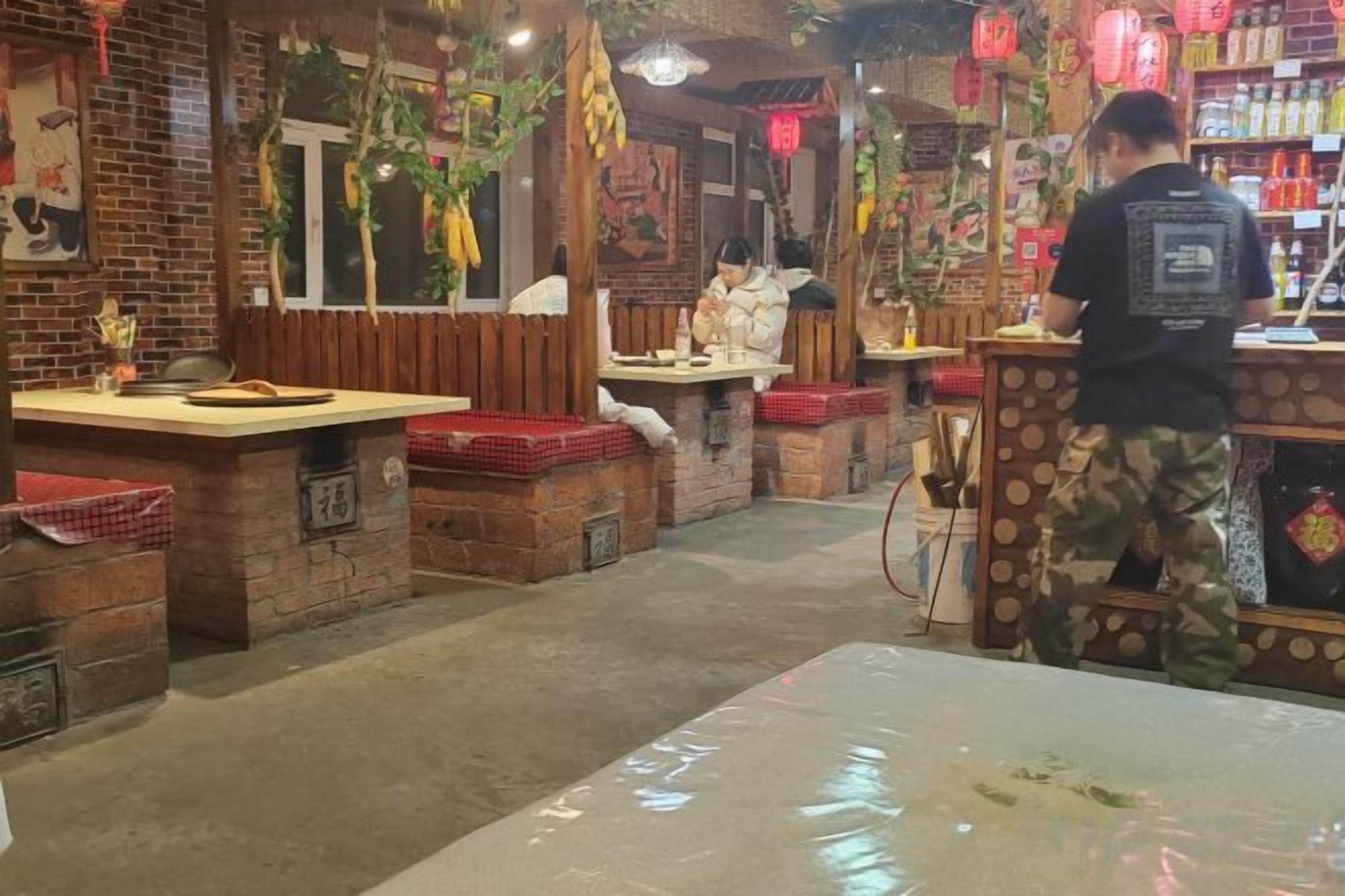 Een restaurantinterieur met bakstenen muren, houten tafels en hangende decoraties.