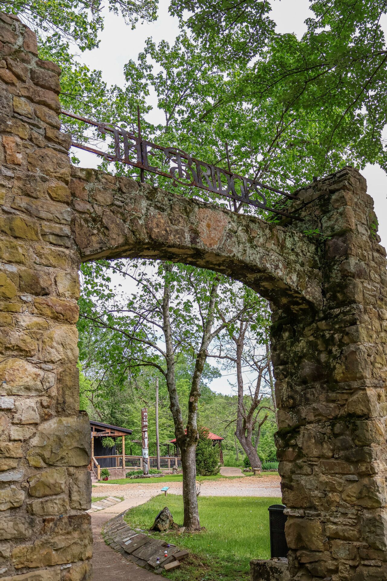 An ancient stone archway with a rustic wooden structure behind it.