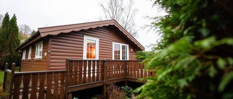 A wooden cabin with a porch and a small deck.