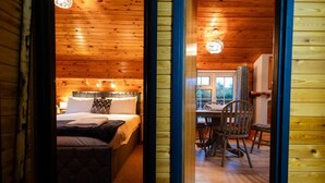 Ein gemütliches Holzblockhaus-Zimmer mit einem Bett, einem Schreibtisch und einem Sessel.