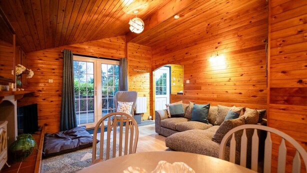 Ein gemütliches Blockhaus mit Holzwänden, einer Couch, einem Esstisch und einem Kamin.