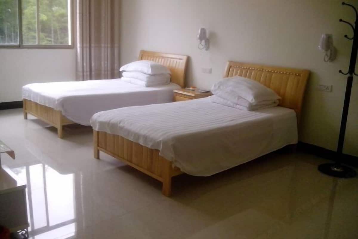 A hotel room with two single beds, a bedside table, and a floor lamp.