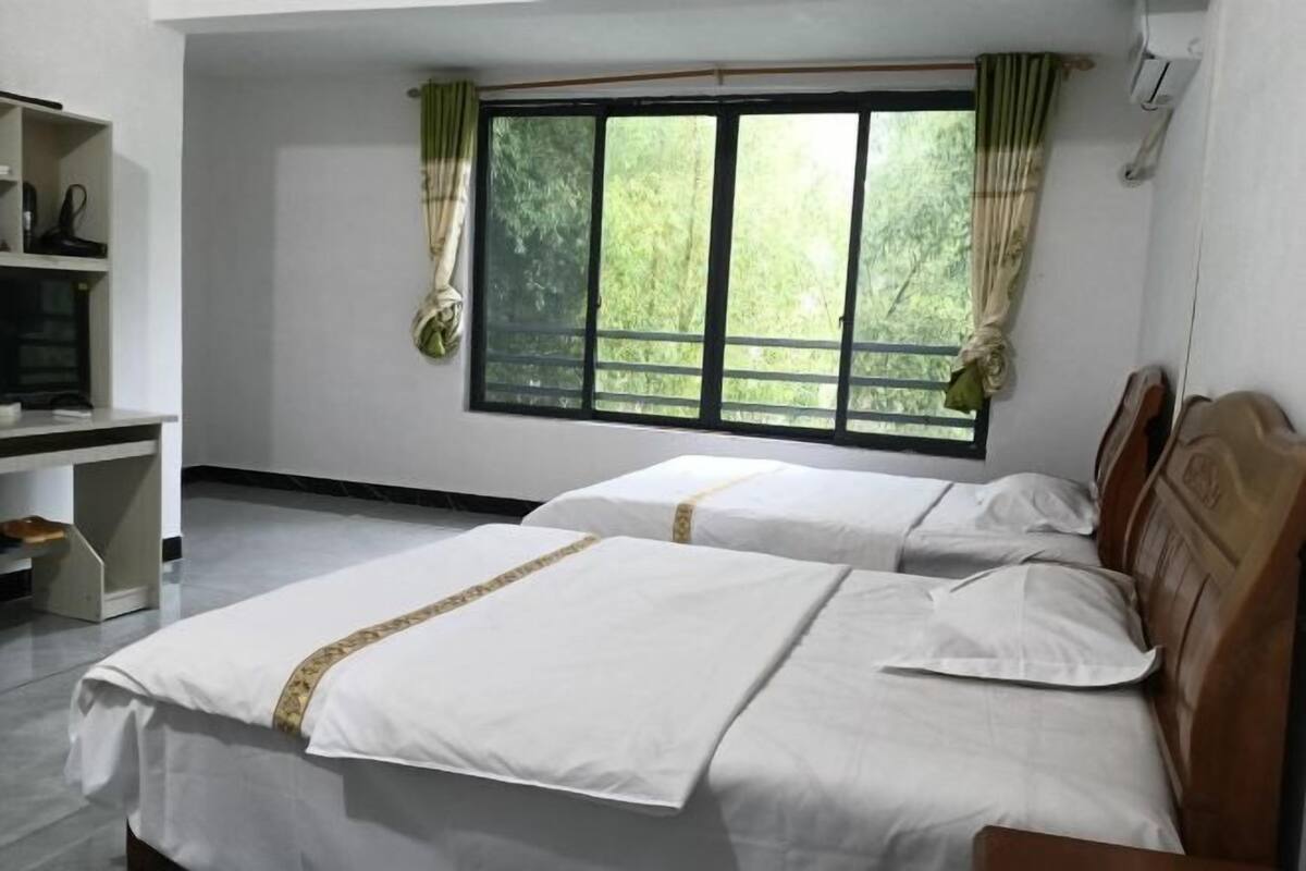 A hotel room with two beds, a desk, and a window with curtains.