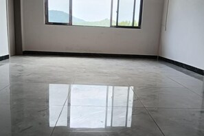 Una habitación con un ventanal grande, un suelo de baldosas brillantes y una pared blanca lisa.