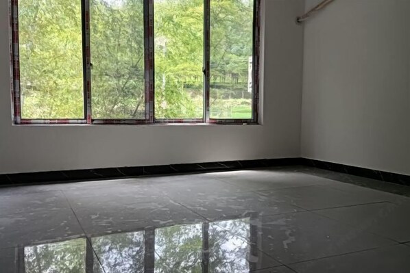Una habitación con un ventanal grande, piso de baldosas y pared blanca.