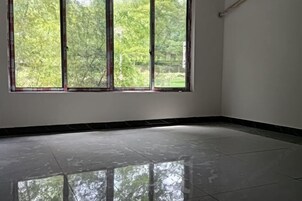 Quarto com uma janela grande, piso de azulejos e parede branca.