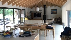 A spacious living area with a wooden ceiling, a dining table, and a kitchen area with a stove.
