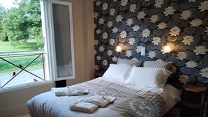 Un dormitorio con una cama grande, una ventana que ofrece vistas al exterior y una pared decorada con un estampado floral.