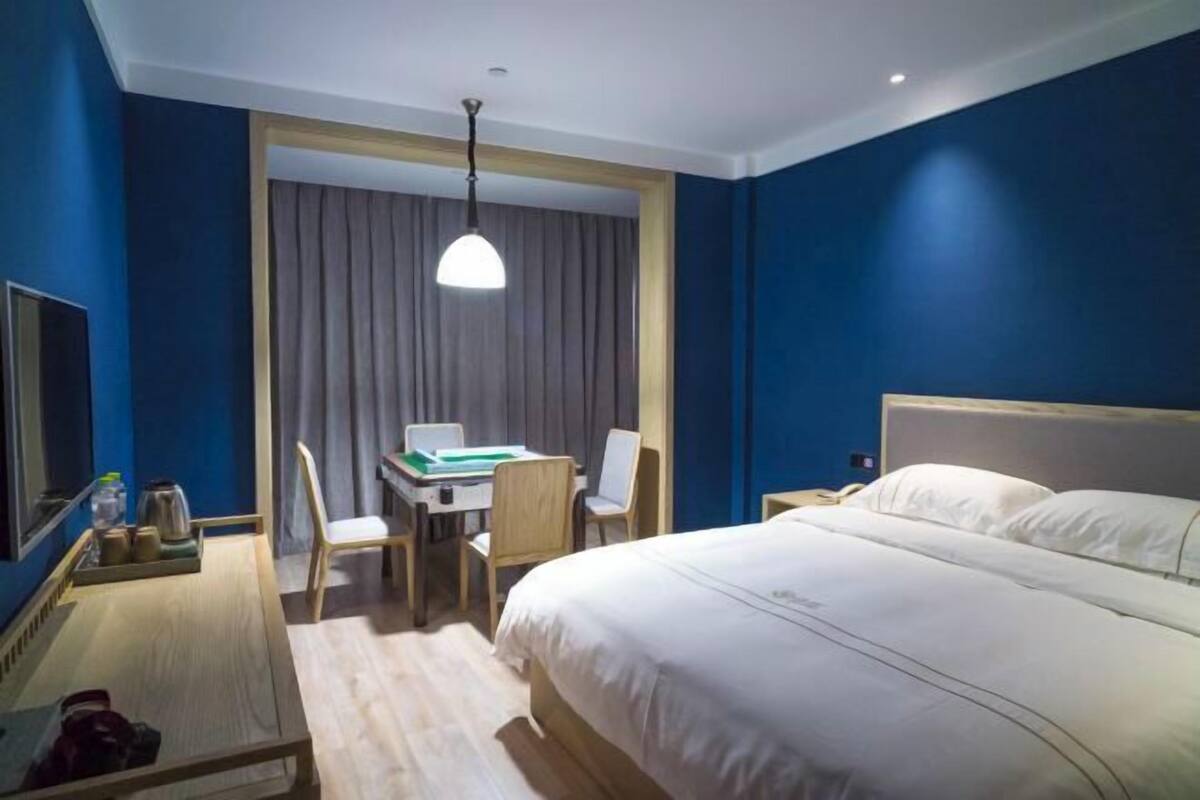 Une chambre d’hôtel avec un grand lit, un bureau avec un ordinateur portable, une chaise et une télévision.