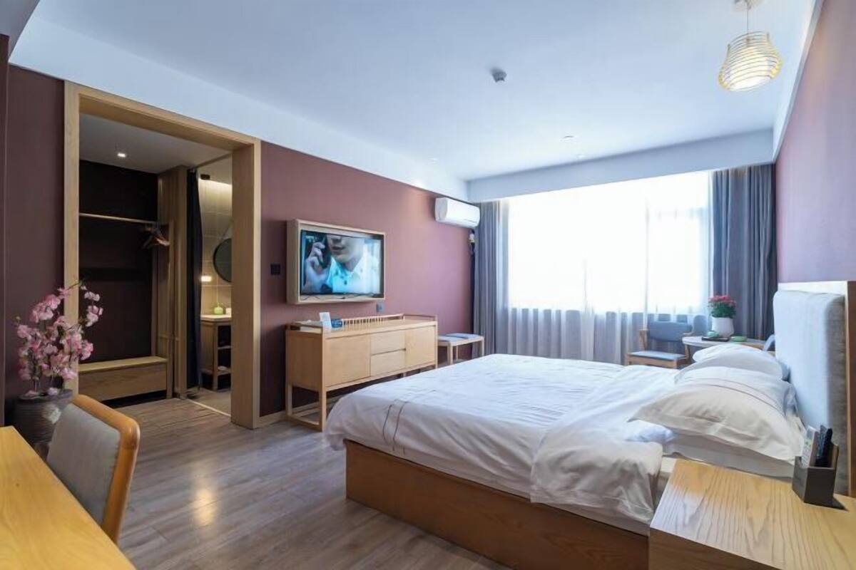 Une chambre d’hôtel avec un lit, un bureau, une télévision, une armoire et une fenêtre.