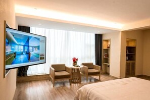 A hotel room with a bed, a TV, two armchairs, a small table with a vase, and a wardrobe. - Jiusu Culture Hotel (Suichang)