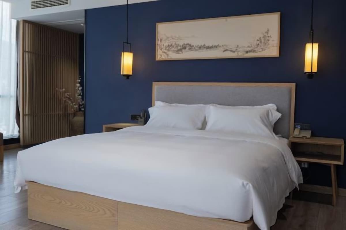 A bedroom with a large bed, wooden headboard, bedside tables, and wall-mounted lamps.