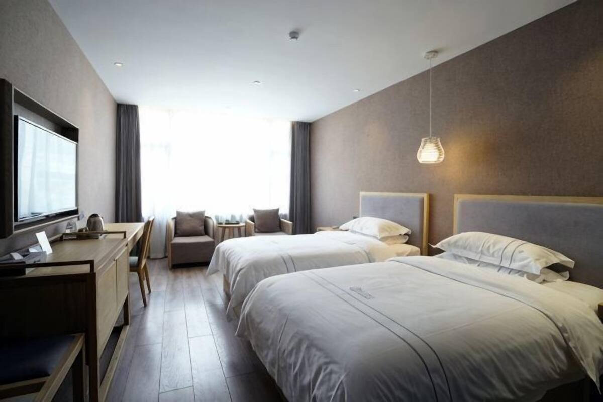 Une chambre d’hôtel avec deux lits, un bureau et une télévision.