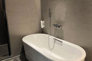 Uma casa de banho moderna com uma banheira independente, um chuveiro manual e um porta-toalhas.