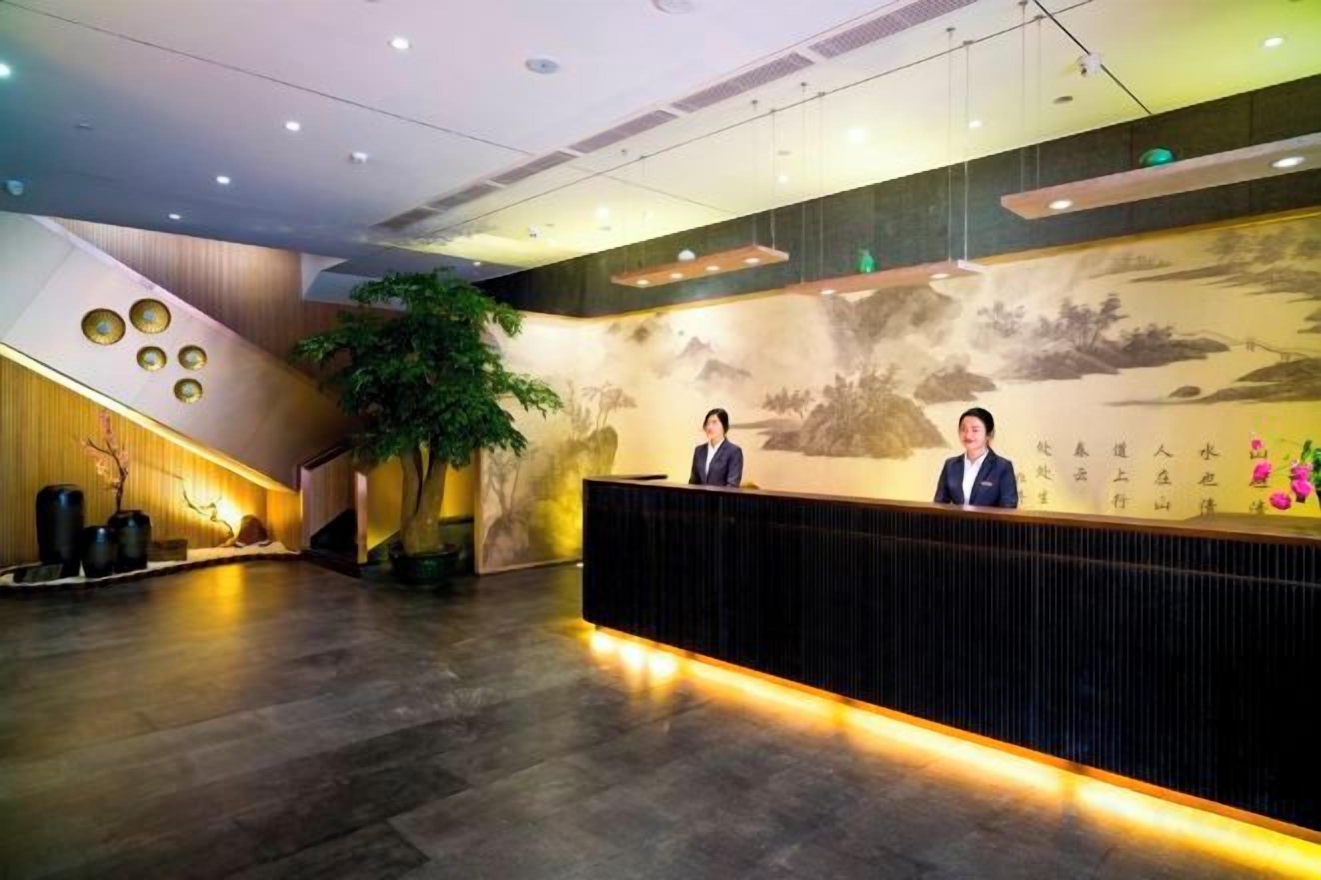 A reception area with a receptionist, a large wall mural, and a staircase.