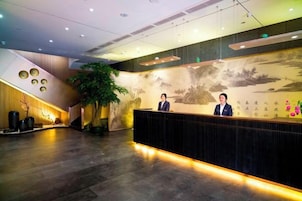 Zona de recepción con recepcionista, un mural grande en la pared y una escalera.