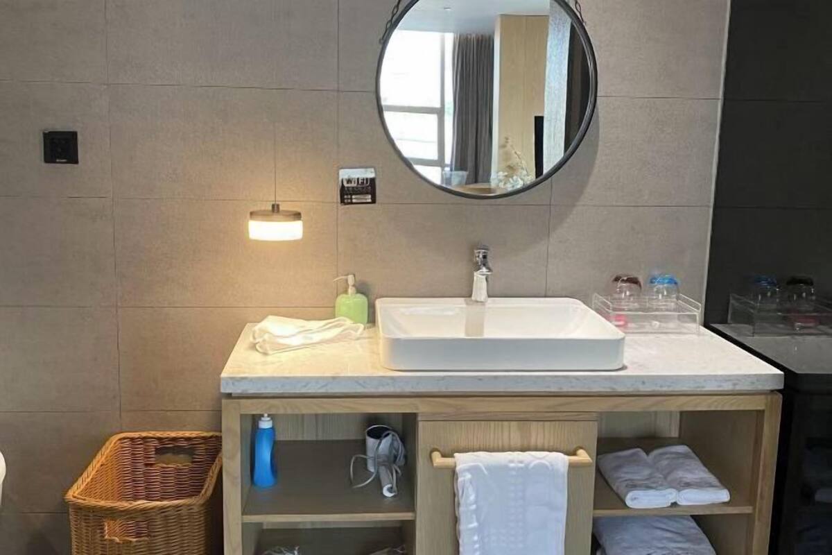 Une salle de bain avec un lavabo blanc, un miroir, un porte-serviettes et un panier en osier.