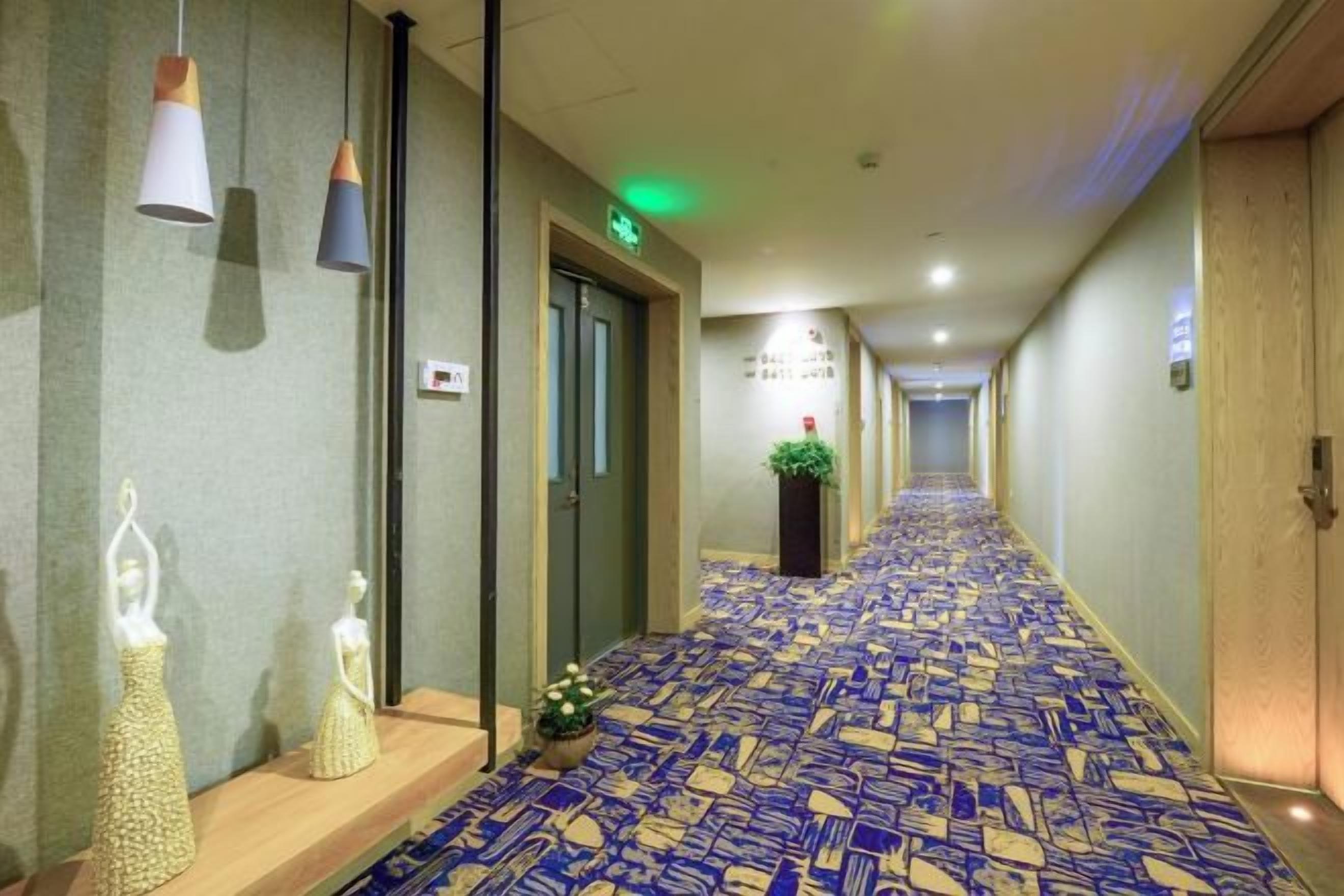 Un pasillo de hotel con alfombra estampada, una recepción y una planta.