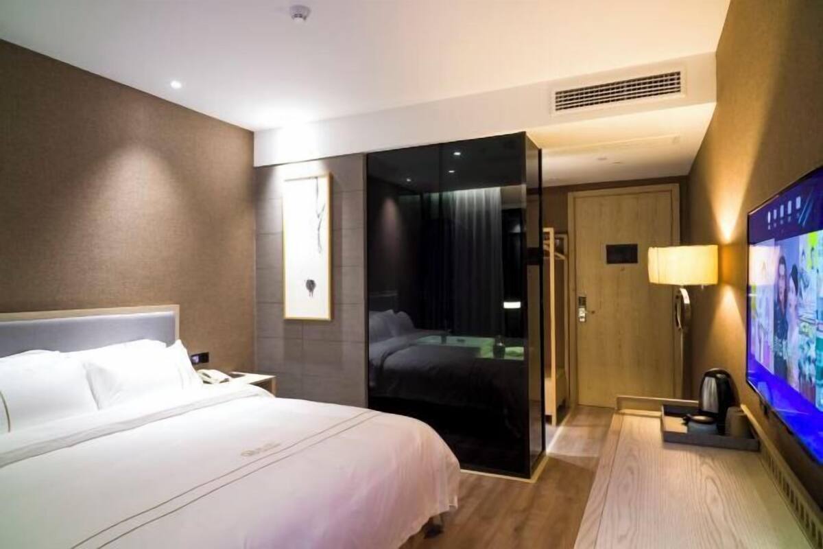 Une chambre d’hôtel avec un lit, une télévision, un bureau et une salle de bain, visibles à travers une porte ouverte.