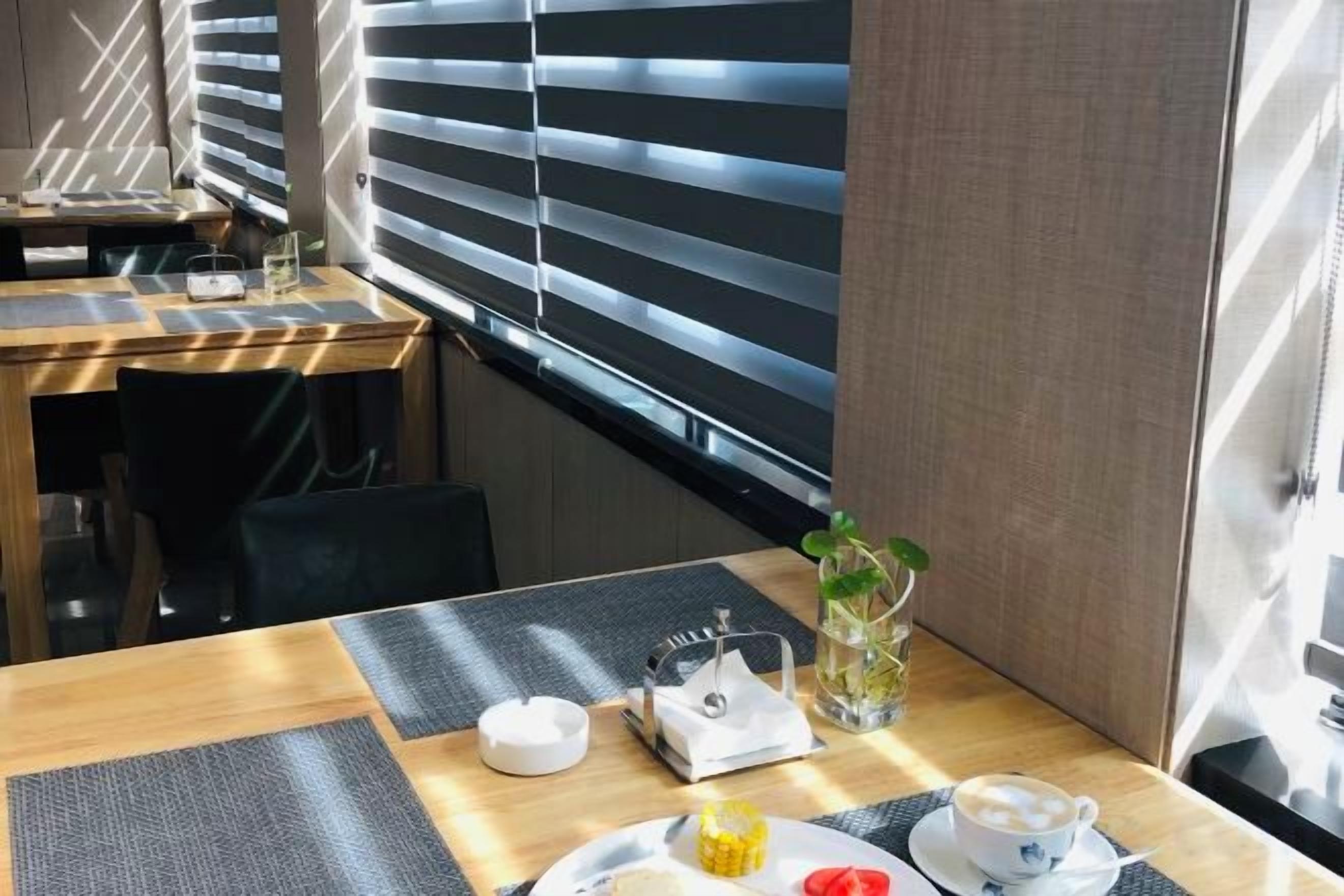 A hotel room with a dining table set with a teapot, cup, and a small vase with a plant.