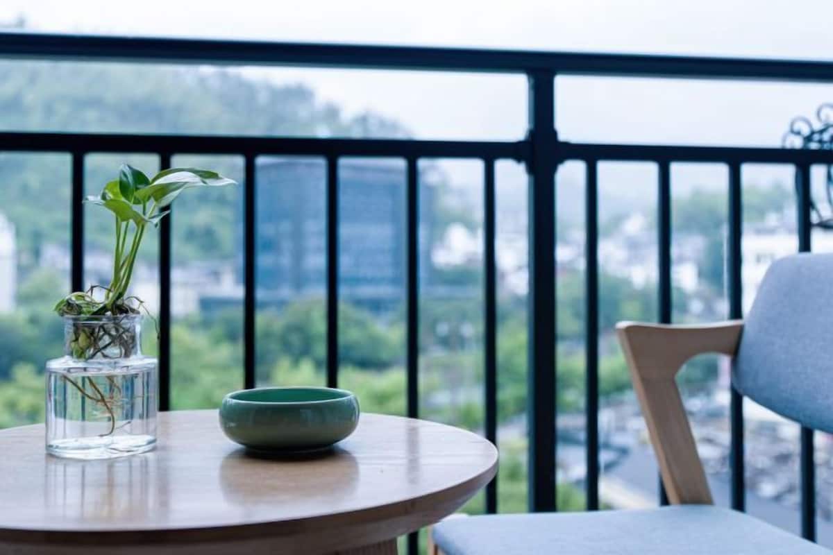 A round table with a vase and a bowl on a balcony with a railing.