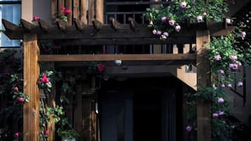 A wooden pergola with climbing roses and a potted plant.