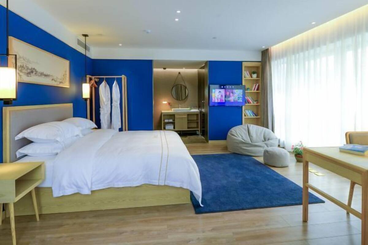 Une chambre d’hôtel moderne équipée d’un grand lit, d’un bureau, d’une chaise, d’une télévision et d’une bibliothèque.