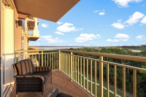A balcony with a wicker sofa and a view of a coastal landscape.