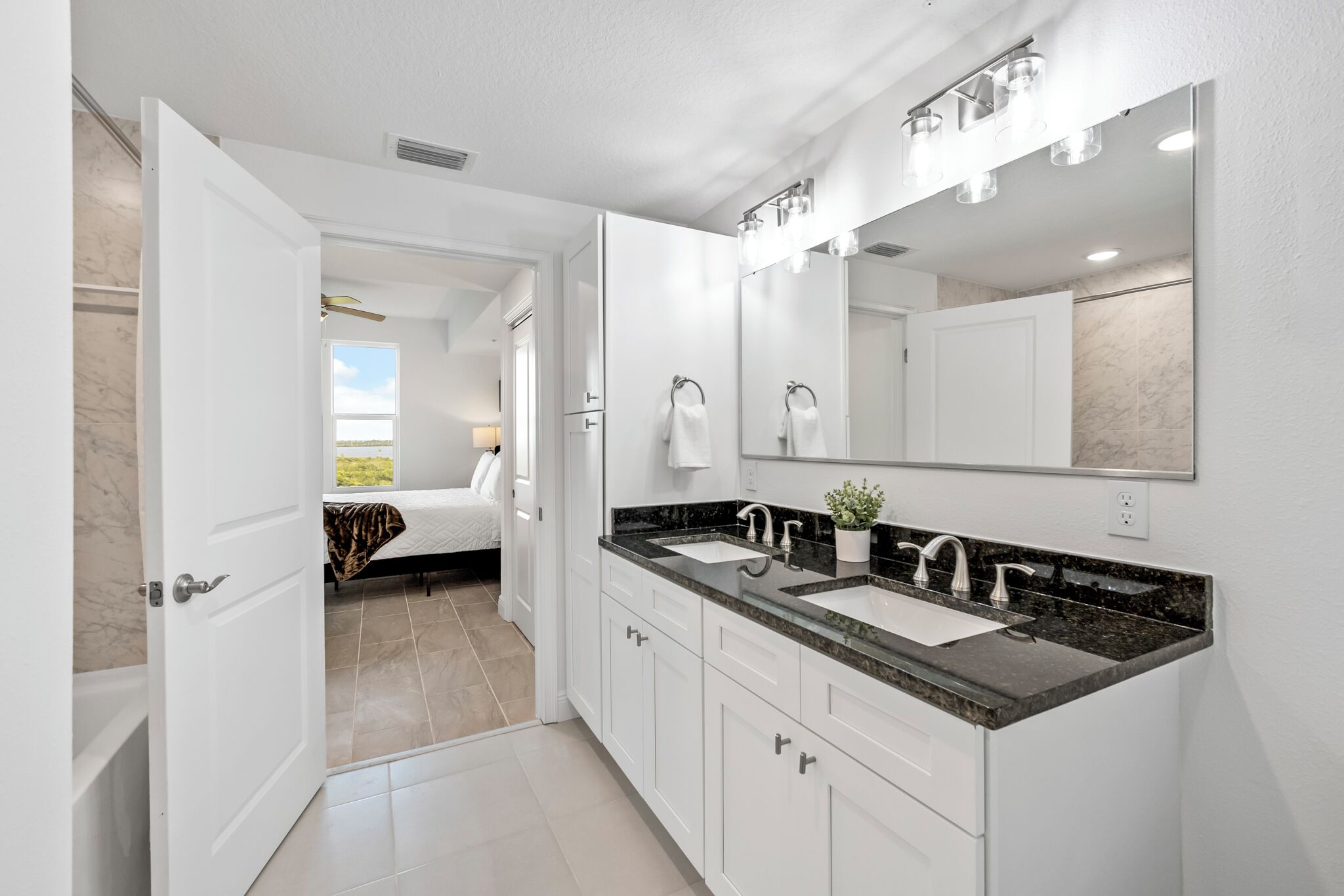 A modern bathroom with a double sink, a large mirror, and a walk-in shower.