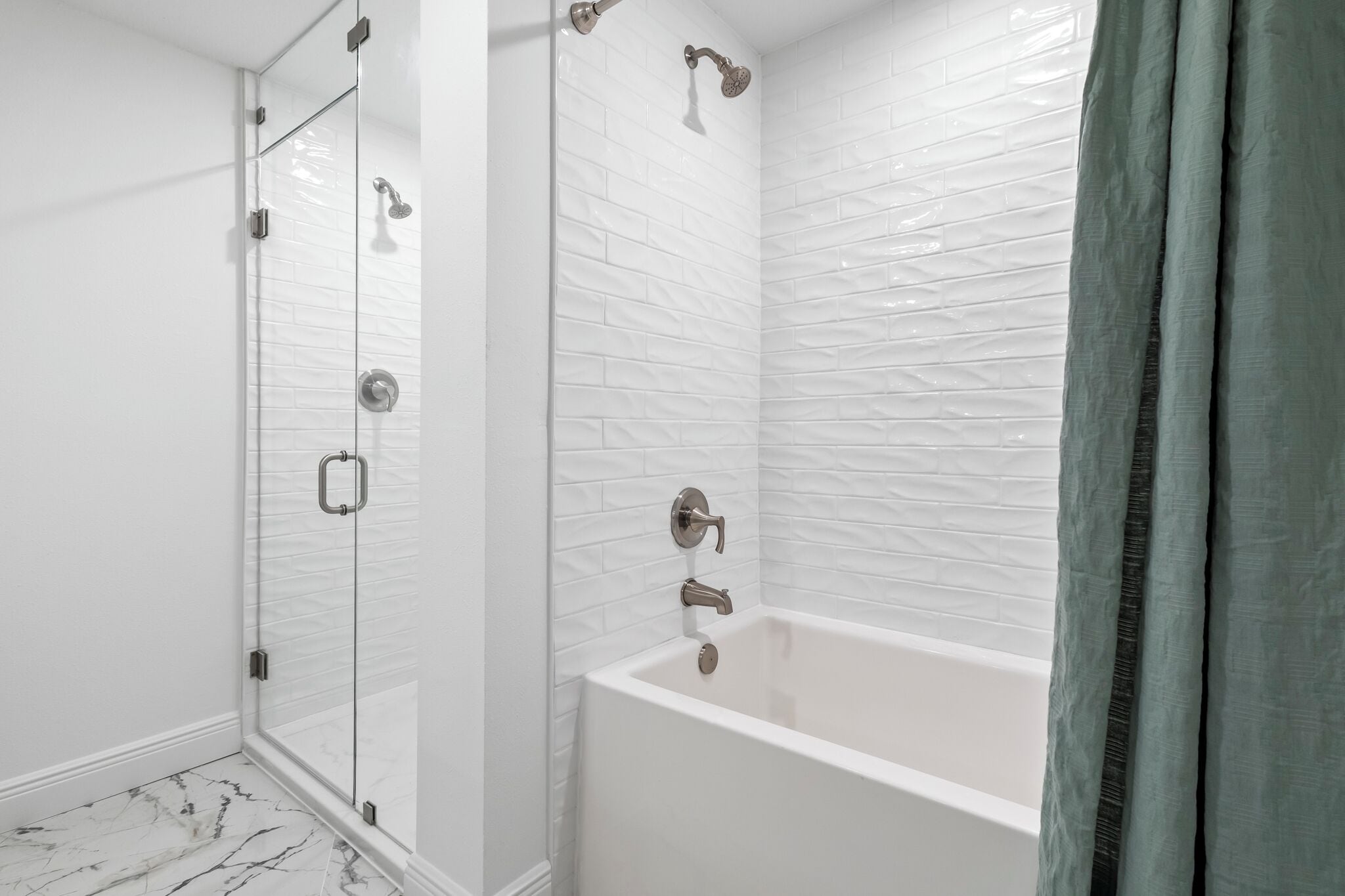 A modern bathroom with a glass-enclosed shower, a freestanding bathtub, and white textured walls.