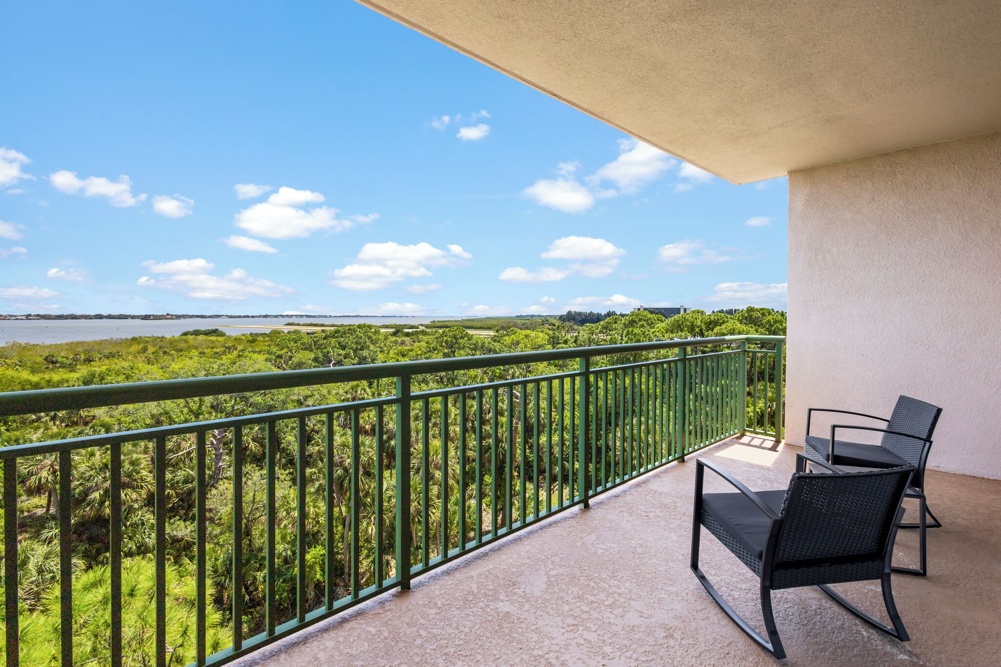 A balcony with a view of a green landscape and a body of water.